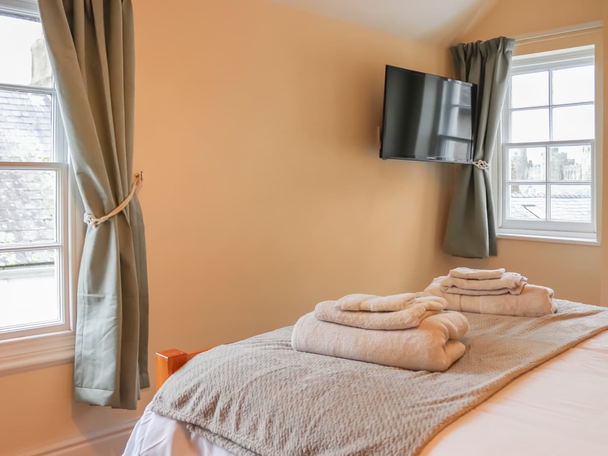 Double bed beside two cottage windows